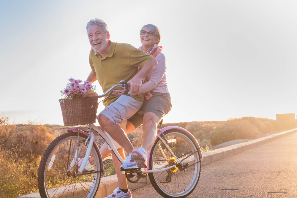 joy and happiness for adult married couple start and have fun traveling on the same bike in outdoor activity with sun backlight on the background. clear and bright image for smile and laugh people.